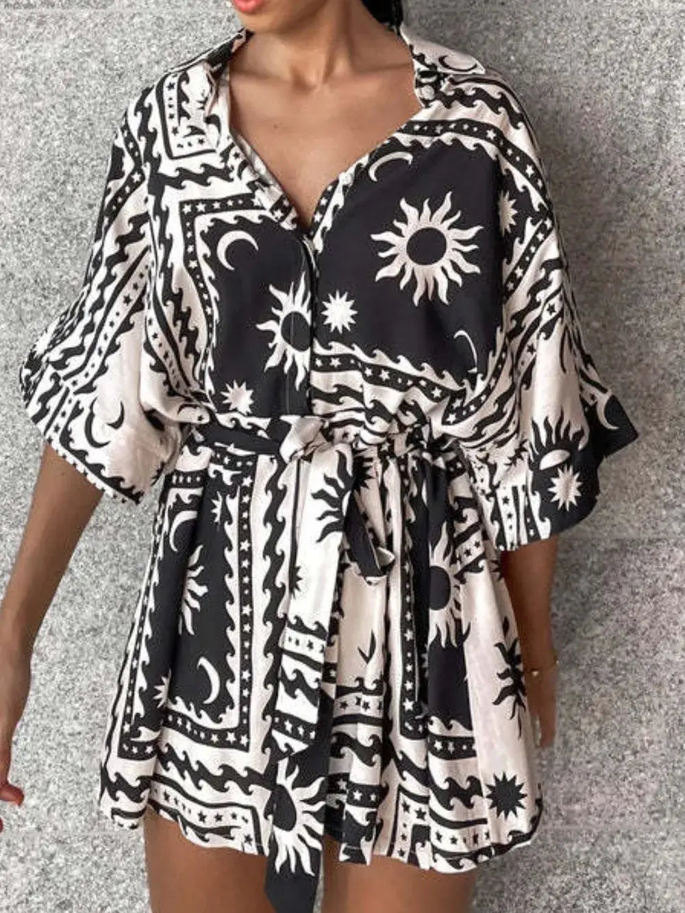 Printed tie waist half sleeve romper featuring a bold black and white sun pattern, ideal for casual summer outings.