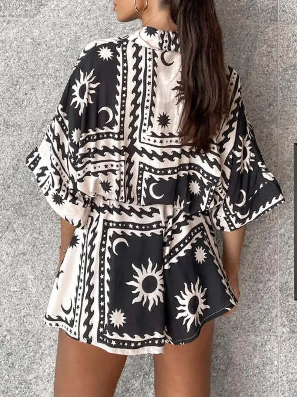 Printed tie waist half sleeve romper featuring a chic black and white pattern with a stylish back view.